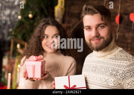 Couple joyeux dans les sweaters qui ont des cadeaux de noël. Banque D'Images