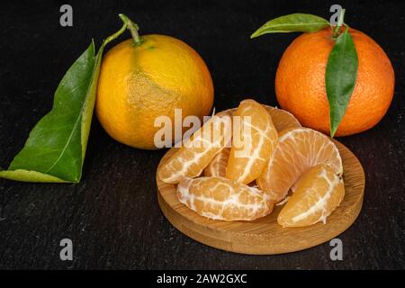 Groupe de deux tout sept morceaux de mandarine orange frais sur les montagnes russes rondes en bambou sur la pierre grise Banque D'Images