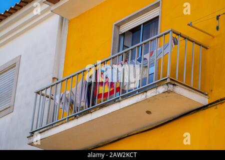 Vêtements et serviettes suspendus sur une ligne de linge à sécher sur un balcon d'un bâtiment jaune, typique du Portugal Banque D'Images