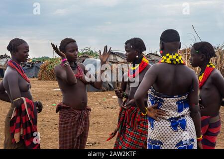 Omorate, Ethiopie - Nov 2018: Les jeunes hommes et femmes portent des vêtements traditionnels tribales et des colliers qui parlent les uns avec les autres. Vallée de l'Omo Banque D'Images