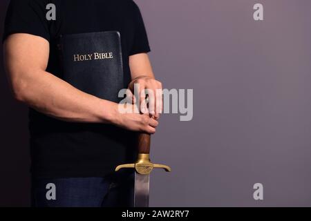 Un jeune homme fort vêtu de façon décontractée, prêt à la Bible et à l'épée Banque D'Images