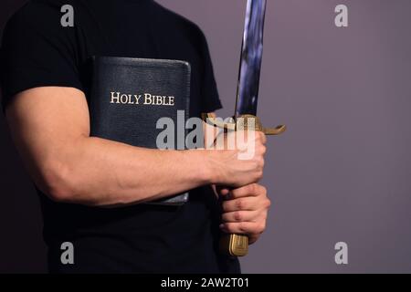 Un jeune homme fort vêtu de façon décontractée, prêt à la Bible et à l'épée Banque D'Images