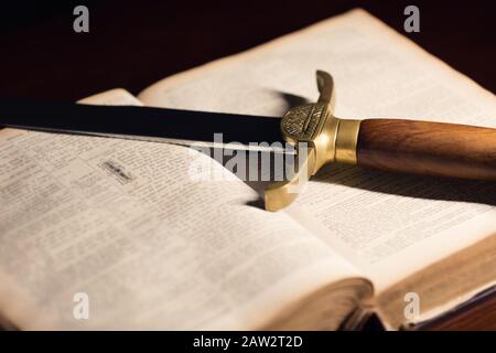 Épée ancienne à côté d'une ancienne Bible ouverte de 150 ans Banque D'Images