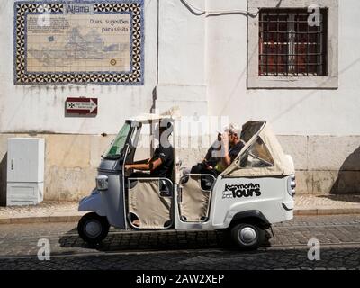 Les touristes qui voyagent à bord d'un véhicule Tuktuk pour des visites touristiques à Lisbonne, au Portugal Banque D'Images