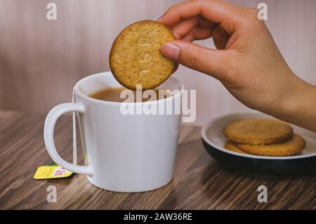 Thé au lait et biscuits main féminine Banque D'Images