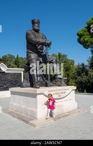 Yalta, Crimée - 09/04/2019: Une petite fille à l'immense monument de l'empereur de Russie Alexander III dans le parc Livadia. Banque D'Images