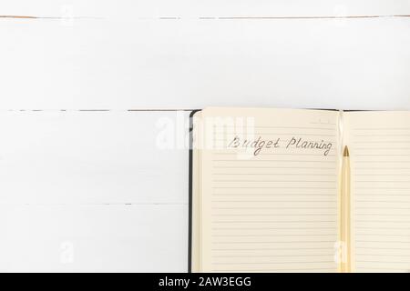 Vue de dessus de l'ordinateur portable avec des mots manuscrits Budget Planning et stylo sur une table en bois blanc. Couche plate avec espace de copie. Banque D'Images
