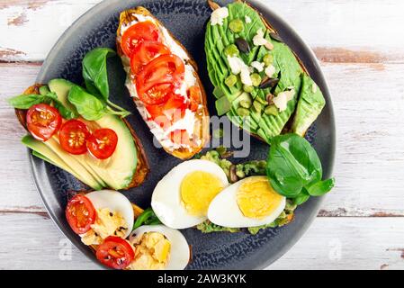 Toasts de patate douce avec avocat, œufs durs, tomates et graines de sésame sur fond rustique blanc. Concept de repas sain. Cuisine propre, plats du Pescetarian, vue sur le dessus Banque D'Images