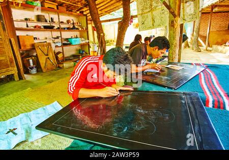 Bagan, MYANMAR - 25 FÉVRIER 2018: Le jeune artisan fait les photos sur les panneaux laqués, à l'aide d'aiguilles de gravure et d'autres outils dans les systèmes traditionnels de fabrication de produits de base Banque D'Images