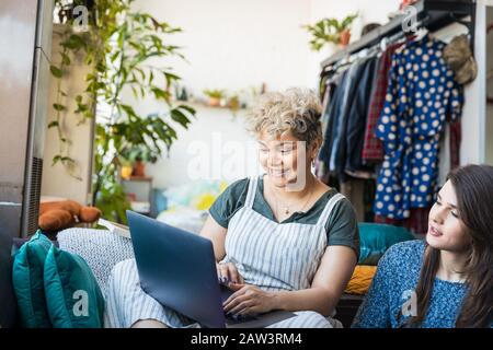 Ami regardant une femme utilisant un ordinateur portable tout en s'asseoir dans le salon à la maison Banque D'Images