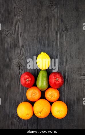 Les fruits mûrs et les agrumes se trouvent symétriquement sur une ancienne table en bois noir. Banque D'Images