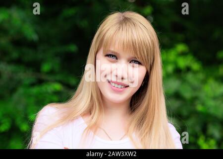 Femme heureuse dehors dans le parc en été. Gros plan portrait beau sourire toothy soleil fille étudiant sourire souriant regardant vous appareil photo City Park backg Banque D'Images