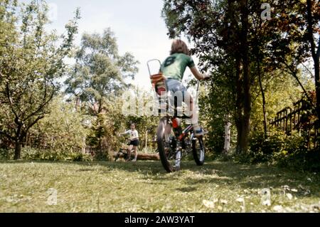 Un frère et une sœur jouant sur leurs vélos Raleigh Chopper American Export et Tomahawk dans leur jardin arrière en 1973 dans la banlieue de Londres Royaume-Uni. Banque D'Images