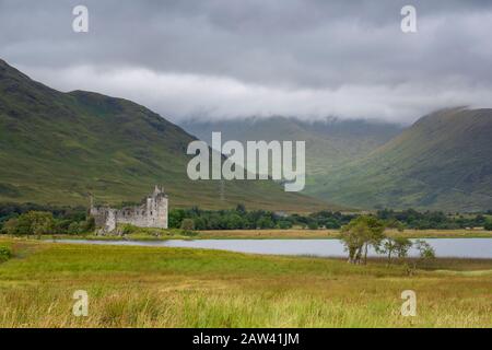 Vue panoramique sur le château de kilchurn à travers loch Awe lors d'une journée de pluie en Ecosse, avec un nuage bas au-delà des montagnes. Banque D'Images