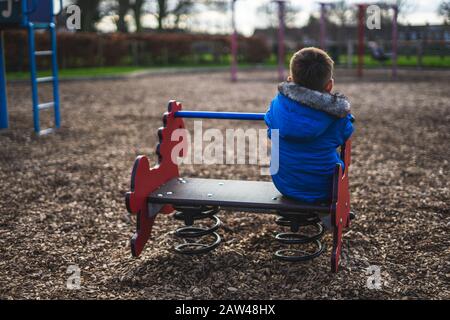 le dos d'un petit garçon jouant seul dans un stationnement Banque D'Images