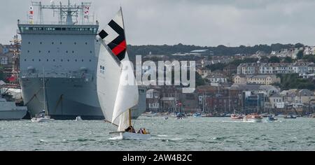 Bateau de travail traditionnel de Falmouth en pleine voile dans la brise de l'estuaire de la FAL course contre le navire naval gris moderne et l'horizon de Falmouth Banque D'Images