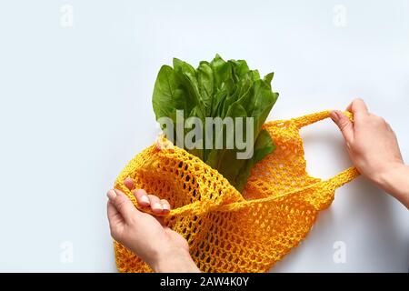 Jeunes femmes mains mettre salade coton sac d'épicerie. Sac écologique réutilisable pour les achats. Concept zéro déchet. Banque D'Images