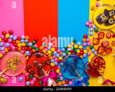 sucettes aux fleurs et aux baies sur fond coloré. Aîné, violet, fleur de maïs, framboises, canneberges, fraises sauvages. Multicolore mixte Banque D'Images