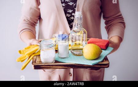 Concept de nettoyants naturels. Femme tenant des ingrédients écologiques pour le nettoyage à la maison, vinaigre blanc, citron, bicarbonate de soude, concept d'acide citrique. Banque D'Images