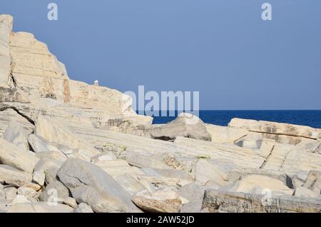 Falaise de marbre, paysage marin, ciel bleu clair et petite pile de pierres zen de marbre sur roche de marbre solide Banque D'Images