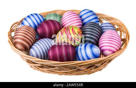 Des œufs de Pâques ornés colorés se piquant dans un panier en osier. Coquilles d'œufs rayées à la main enveloppées de fils à coudre en coton fin collé. Coquilles vides ornées. Banque D'Images