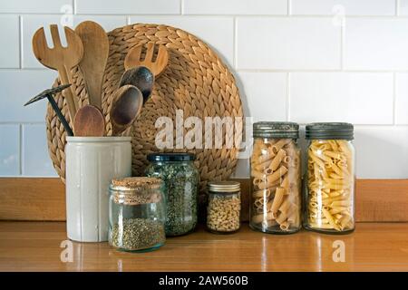 Ustensiles de cuisine écologiques avec pots de stockage en verre anciens et recyclés contre les carreaux blancs, concept zéro déchet Banque D'Images