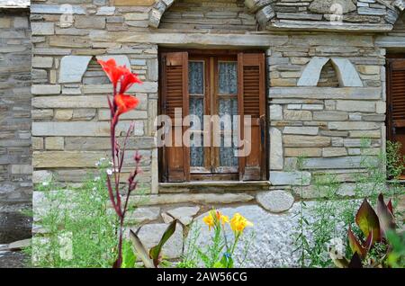 Détail arhitecture, fenêtre en bois avec volets sur ancienne maison en pierre vintage avec fleurs en premier plan Banque D'Images