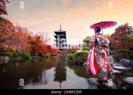 Jeune fille japonaise voyageur dans la robe kimino traditionnelle debout dans le temple Toji avec pagode en bois et feuille d'érable rouge en automne saison à Kyoto, Jap Banque D'Images