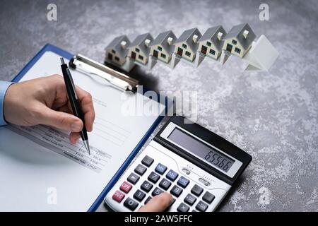 Homme Calculant La Facture Devant Les Modèles De Maison Sur L'Escalier Flèche Croissante Banque D'Images