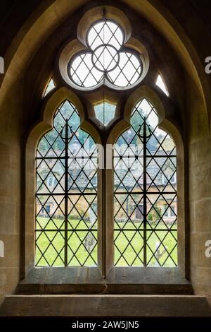 Bâtiments du village de Cotswolds de Snowshill vue par la fenêtre gothique de l'église Saint Barnabas, Gloucestershire, Angleterre, Royaume-Uni Banque D'Images