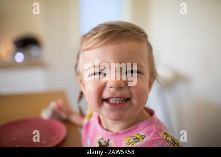 Portrait d'une petite fille mignonne souriant au moment du repas. Banque D'Images