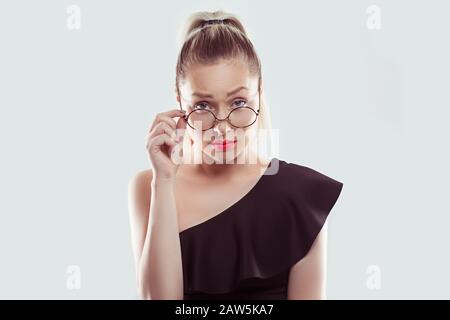 Sceptique jeune femme suspecte tenant des lunettes de vue vers le bas regardant votre appareil photo isolé sur fond de mur bleu clair blanc Banque D'Images