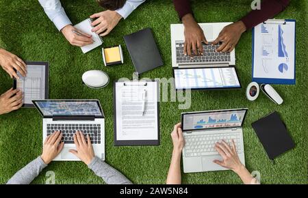 Vue Aérienne Des Hommes D'Affaires Sur L'Herbe Avec Les Ordinateurs Portables Et Le Travail Sur Tablette Numérique Banque D'Images