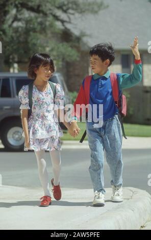 Frère et sœur asiatique-américain qui marchent à la maison de l'école ensemble à Austin, Texas. Banque D'Images