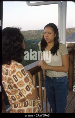 La jeune fille asiatique-américaine parle à sa mère sur le porche arrière de leur maison à Austin, Texas. Banque D'Images