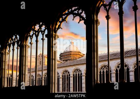 Le dôme de la cathédrale de Pise Duomo est visible sous un coucher de soleil coloré de l'intérieur des fenêtres voûtées en pierre de Camposanto dans la ville toscane de Pise, Italie. Banque D'Images