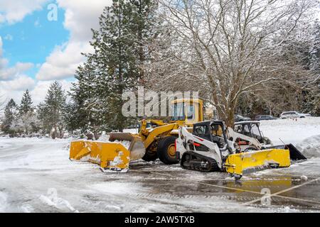 Les véhicules de chasse-neige non marqués s'assoient vides dans un parking après une tempête hivernale dans les montagnes de l'Idaho du Nord, aux États-Unis. Banque D'Images