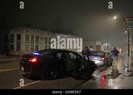 Les officiers de police spéciale de Detroit arrêtent un véhicule et parlent au conducteur lors d'une nuit de pluie à Detroit, Michigan, États-Unis Banque D'Images