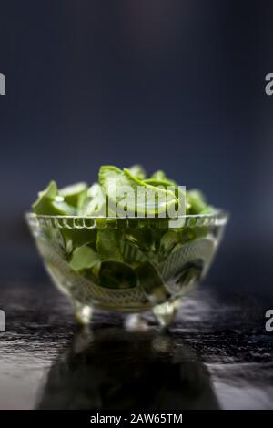 Coupe brute de gel d'aloevera ou d'aloe vera dans un bol en verre sur la surface en bois avec son reflet sur la surface. Banque D'Images