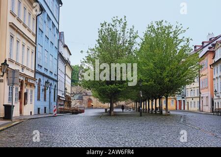 Une avenue d'arbres dans une place avec une rue pavée encadrée par des immeubles d'appartements. Tôt le matin de printemps sur Na Kampě, Malá Strana, Tchéquie Prague. Banque D'Images