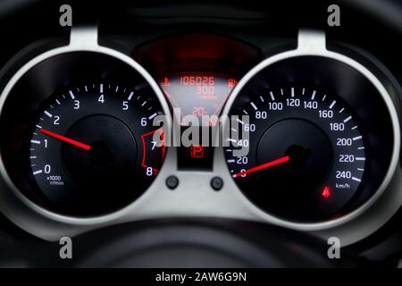 Le tableau de bord de la voiture est blanc brillant avec des flèches rouges la nuit avec un compteur de vitesse, un tachymètre et d'autres outils pour surveiller l'état du vehi Banque D'Images