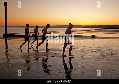 Portobello Beach, Édimbourg, Écosse, Royaume-Uni. 7 février 2020. Température de moins 2 degrés, mais ces jeunes nageurs sauvages Joe, Rachel, Andrew et Joe se appelant la nouvelle histoire les Nageurs sauvages ont apprécié le plongeon dans le Firth of Forth au lever du soleil. Banque D'Images