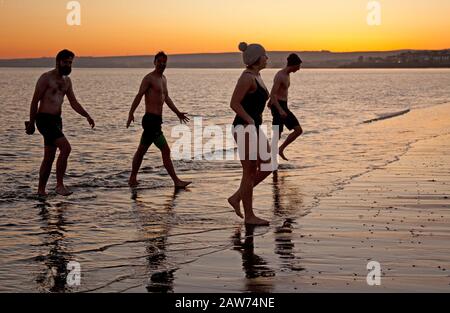 Portobello Beach, Édimbourg, Écosse, Royaume-Uni. 7 février 2020. Température de moins 2 degrés, mais ces jeunes nageurs sauvages Joe, Rachel, Andrew et Joe se appelant la nouvelle histoire les Nageurs sauvages ont apprécié le plongeon dans le Firth of Forth au lever du soleil. Banque D'Images