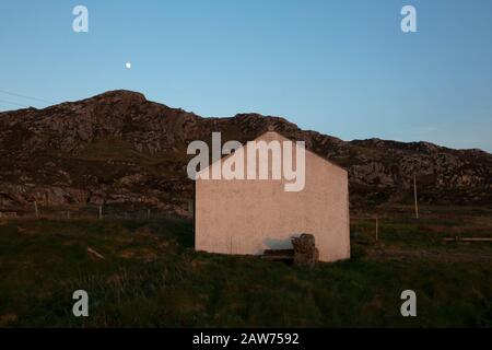 L'extrémité pignon d'un cottage photographié au coucher du soleil sur l'île Hebridée intérieure de Colonsay sur la côte ouest de l'Écosse. L'île est située dans la zone du conseil d'Argyll et de Bute et a une superficie de 4 074 hectares (15,7 miles carrés). Aligné sur un axe sud-ouest à nord-est, il mesure 13 km de long et atteint 4,8 km à son point le plus large, en 2019 il comptait 136 adultes et enfants. Banque D'Images