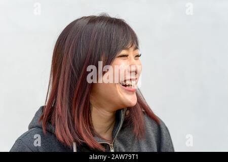 Heureuse jeune femme asiatique vivace à manger quand elle regarde à côté Banque D'Images