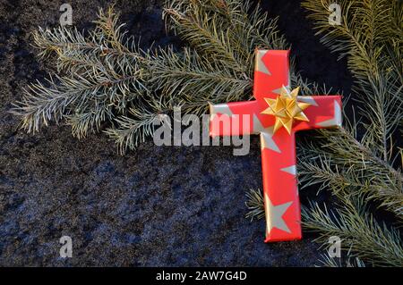 Croix enveloppée en papier comme un présent à Noël comme un symbole, que Jésus n'était pas né pour vivre sur terre comme un roi riche, mais pour mourir pour nos péchés Banque D'Images