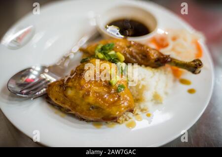 Poulet frit dans une sauce collante sur le riz garni d'oignon et de sauce rouge. Cuisine asiatique de gros plan Banque D'Images