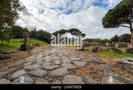 Rome, Italie - 02 février 2020: Fouilles archéologiques d'Ostia Antica, ancien pavé du grand déciman, avec des statues sur le bord de la route. Banque D'Images