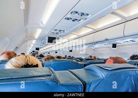 Lisbonne, Portugal - 9 juin 2013: À l'intérieur d'une cabine d'avion - sièges de passagers pendant le vol avec moniteurs sur le plafond de cabine - rangées avec passagers Banque D'Images