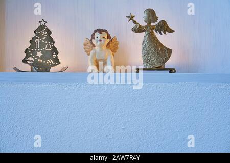Décoration de Noël avec des anges et des bougies dans une étagère blanche pure dans un mur blanc, l'or argent brillant humeur et espace de copie Banque D'Images